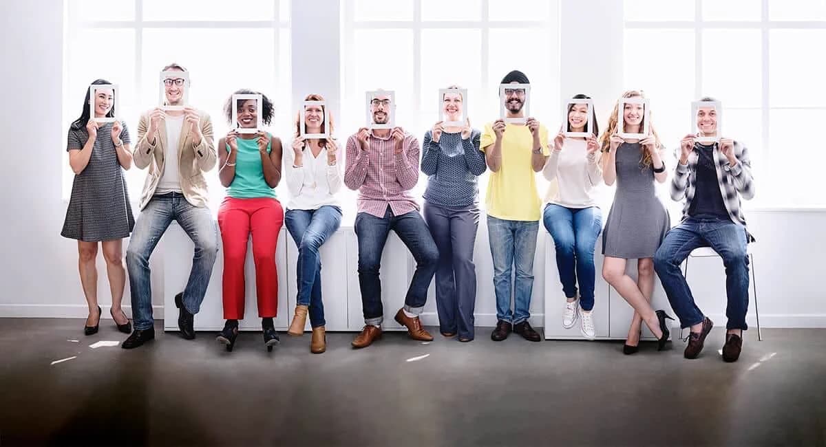 Eine vielfältige Gruppe hält Bilderrahmen vor ihre Gesichter